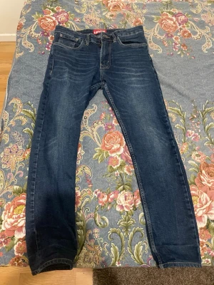 Mörkblå raka jeans från Levi's - Snygga mörkblå jeans från Levi's med klassisk rak passform och fem fickor. Jeansen har subtila slitningar framtill och kontrastsömmar. Tillverkade i slitstark denim med en tidlös look och röd Levi's-detalj på bakfickan.