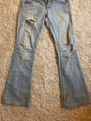 Ljusblå bootcut jeans med slitningar - Säljer ett par ljusblå bootcut jeans med slitna detaljer och hål på båda benen. Köpta på vinted o aldrig använda då de är för små. Jättebra skick.