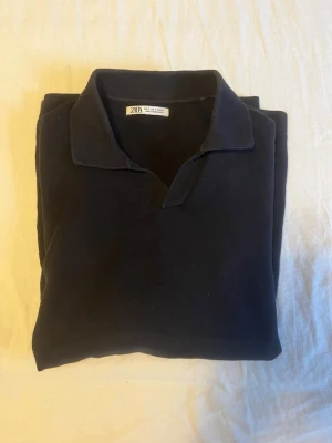  piké t-shirt från Zara - En stilren piké t-shirt från Zara med klassisk krage och kort ärm. Tillverkad i mjuk bomull som känns skön mot huden. Perfekt för en clean och enkel look.