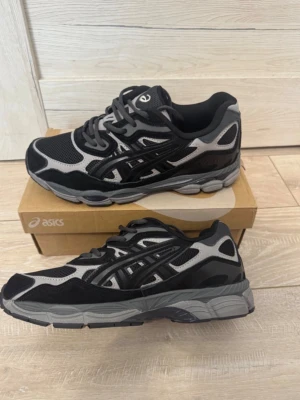 Svarta och grå Asics sneakers - 8 ASICS GEL-NYC i storlek 43 8 Säljer ett par snygga och eftertraktade ASICS GEL-NYC i grål svart färgkombination. Skorna är i mycket fint skick och passar perfekt både till vardags och streetwear. V Storlek 43 • Äkta vara V Kvitto finns Bekväma GEL-dämpning Trendig och popular modell V Snabb frakt Skorna är väl omhändertagna och redo för en ny ägare. Se bilder för skick. Hör gärna av dig vid frågor eller om du vill ha fler bilder. Pris:1499kr