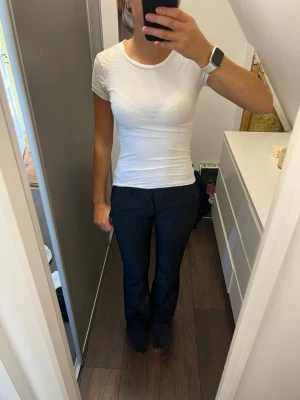 Vit tight t-shirt från Gina Tricot - Klassisk vit t-shirt från Gina Tricot i tight passform. T-shirten har rund halsringning och korta ärmar. Tillverkad i mjuk bomull som känns skön mot huden. Perfekt basplagg att ha i garderoben.
