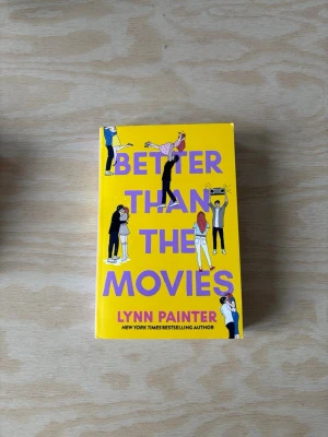 Better Than the Movies bok - En färgglad pocketbok med gul framsida och lila text, skriven av Lynn Painter. Omslaget har illustrationer av ungdomar i olika romantiska situationer. Perfekt för dig som gillar romantisk feelgood och ungdomsromaner.