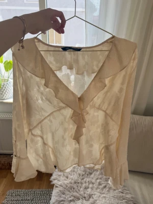 Beige volangblus med v-ringning - Söt beige blus med volangdetaljer och v-ringning. Från Zara. Väldigt använd och det finns en del tecken på användning 🤍