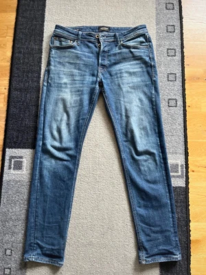 Jack & jones tapered Mike - Snygga blå jeans från Jack & Jones i modellen Tapered/Mike. Jeansen har en tvättad look med klassisk femficksdesign. Tillverkade i denim med rak passform som smalnar av nedtill. Perfekta för en avslappnad och trendig stil.