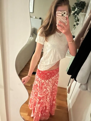 Rödvit långkjol - ⚠️skriv innan ni köper⚠️Säljer en flowy långkjol i rött och vitt med blommigt mönster. Kjolen har en bred, smockad midja och är gjord i ett lätt material som passar perfekt till varmare dagar. Superskön och snygg till både t-shirt och linne. Står ingen storlek men jag brukar ha mellan xs och s.