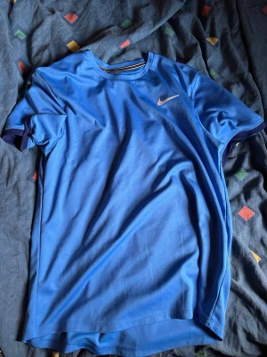 Säljer en blå Nike dri fit T-shirt - Hej! Säljer en äkta blå Nike dri fit tennismodell  T-shirt i strl m, vill inte ha den längre