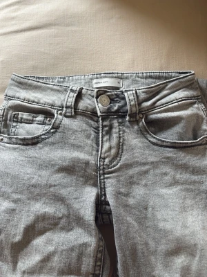 Grå tvättade jeans med fickdetaljer - Säljer ett par grå tvättade jeans med snygga fickdetaljer både fram och bak. 
