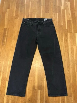 Svarta raka jeans med hög midja - Snygga svarta jeans med rak passform och hög midja. Klassisk femficksmodell med knappgylf och bälteshällor. Jeansen är tillverkade i ett kraftigt denimtyg som ger en cool och avslappnad look.