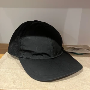 Gucci nylon keps - Sällsynt keps från Gucci med diskret GG-monogram på framsidan och meshpaneler på sidorna och bak. Justerbar SnapBack men saknar tyvärr alla knappar som har hoppat av☹️. Kepsen har även lite slitningar. Priser går att diskutera 