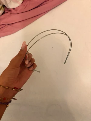 Tunn dubbel metallhårbåge silver - Säljer en minimalistisk hårbåge i silverfärgad metall med två tunna band. Perfekt för att hålla håret på plats och ge en clean look. Enkel och stilren design som passar till många olika frisyrer.