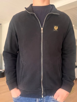 Belstaff tröja  - Säljer en svart belstaff zip tröja i storlek L. Tröjan har används fåtal gånger och är i bra skick! Hör av dig vid mer frågor. 
