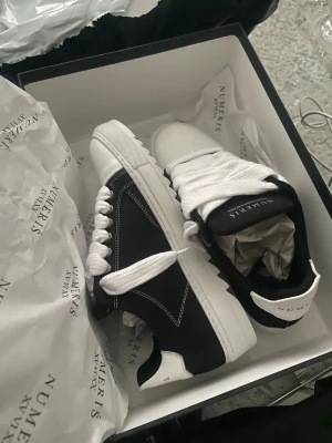 Numeris Acryl black helt nya - Heltt nya Stilrena sneakers från Numeris i svart och vitt med tjock vit sula och breda vita skosnören. Skorna har kontrastsömmar och en klassisk låg siluett. Materialet ser ut att vara en mix av läder och textil. Perfekta för en trendig streetwear-look. storlek 41 men passar även strl 42 eftersom det är size down- Nypris:2900kr inkl frakt 