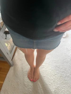 Blå jeanskjol med rå kant - Säljer en klassisk blå jeanskjol i kort modell med rå, fransig kant nedtill. Kjolen har en enkel design utan synliga detaljer som knappar eller dragkedja framtill. Perfekt för dig som gillar en avslappnad och trendig stil. Slutsåld i denna modellen!