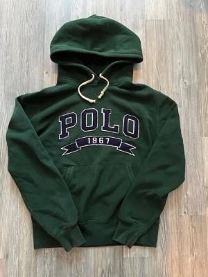 Mörkgrön hoodie med POLO-tryck - Säljer nu en as fet mörkgrön POLO Ralph Lauren hoodie. Storlek M på lappen men känns mer som S. Borde passa någon mellan 175-185 kanske lite längre/kortare beroende på hur man vill att den ska sitta och hur man är byggd.