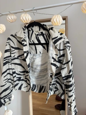Zebramönstrad jeansjacka - Säljer en riktigt cool zebramönstrad jeansjacka i svart och vitt. Jackan har klassisk krage, knappstängning framtill och två bröstfickor med lock. Croppad modell från Gina tricot 