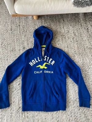 Blå Hollister Ziphoddie, storlek M - Säljs pga storlek, använd ett par ggr med en mindre fläck som kanske går på i tvätten (kan inte garantera) 