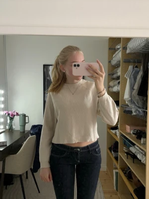 Beige croppad tröja med lång ärm - Säljer en beige croppad tröja med långa ärmar och rund hals. Tröjan har en ribbad struktur och är tillverkad i ett mjukt material som passar perfekt till jeans eller kjol. Enkel och stilren design som är lätt att matcha.