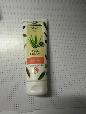 Aphrodite Olive Oil Handkräm Aloe Vera - Helt ny Handkräm från Aphrodite med olivolja och aloe vera, perfekt för torr och narig hud. Tuben är vit med gröna detaljer och har en smidig skruvkork. Innehåller 100 ml och är lätt att ta med i väskan. Plomberad och oöppnad.