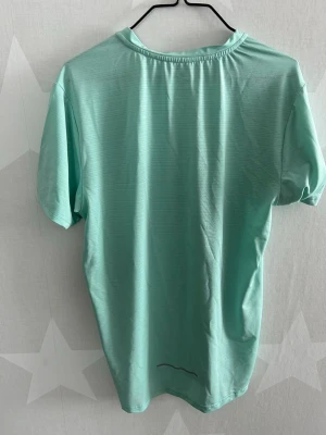 Mintgrön Nike t-shirt - Fräsch mintgrön t-shirt från Nike med diskret logga på bröstet. Tillverkad i ett lätt och svalt material som passar perfekt till träning. Klassisk rund halsringning och korta ärmar för en sportig look. Storlek S men Passar M