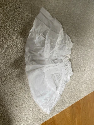 Vit volangkjol i linne - Söt vit kjol med volanger och resår i midjan. Kjolen är tillverkad i ett lätt och luftigt linnematerial, perfekt för varma dagar.