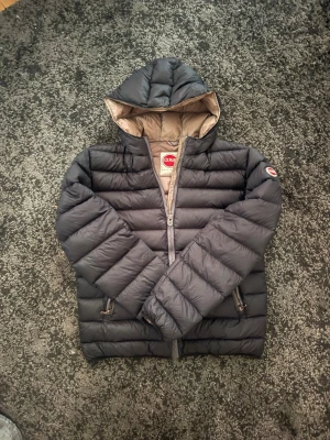 Colmar jacka - Snygg svart dunjacka från Colmar med huva och bruna detaljer. Jackan är i storlek 50 och passar som S/M. Perfekt för kalla vinterdagar samt höst dagar och riktigt skön att bära