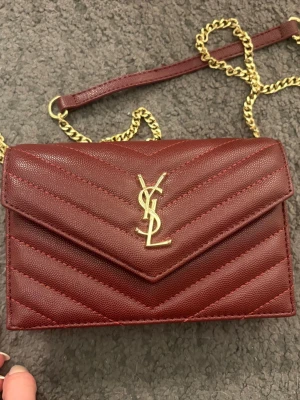 Yves saint laurent väska - Jätte snygg vinröd väska som är köpt på Vietnams marknad. Super bra kvalité på sömmarna och allt sådant, allt som saknar är vatten märket. 