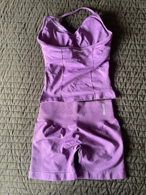 DFYNE impact set - Säljer ett lila träningsset från DFYNE med ett sömlöst linne med smala axelband och matchande cykelshorts med hög midja. Materialet är stretchigt och följsamt, perfekt för gymmet eller yoga. Båda delarna har DFYNE-logga framtill.