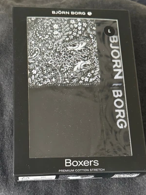 Björn Borg boxerkalsonger 2-pack - Säljer ett 2-pack boxerkalsonger från Björn Borg i storlek L. Ena paret är helsvart med Björn Borg-logga i midjan, det andra har ett svartvitt blommigt mönster. Tillverkade i premium bomullsstretch för extra komfort och bra passform. Oöppnat. Nypris 429:-