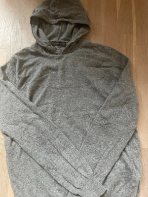 Grå hoodie från Oscar Jacobson - Mjuk och stilren grå hoodie från Oscar Jacobson i storlek S. Tillverkad i ett tunt, skönt material med lång ärm och klassisk huva. Perfekt för en avslappnad look och enkel att matcha med andra plagg.