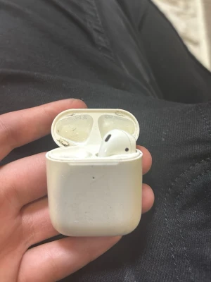 Trådlösa vita hörlurar med laddningsetui - Säljer ett par trådlösa vita hörlurar med laddningsetui. Hörlurarna har en stilren och kompakt design med rundade kanter och magnetiskt lock. Perfekta för musik, poddar och samtal på språng. Laddningsetuiet är smidigt att ta med i fickan.