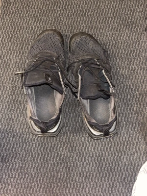 Svarta mesh-sneakers med snörning - Säljer ett par svarta sneakers med ovandel i mesh och klassisk snörning. Skorna har en sportig sula med mönster och detaljer i svart. Perfekta för dig som gillar en stilren och sportig look.
