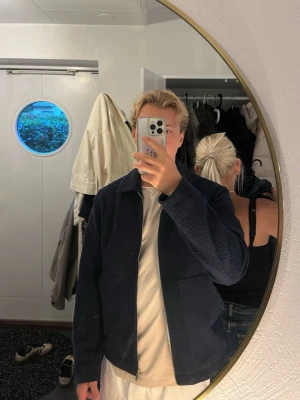 Mörkblå jacka med dragkedja - Säljer en mörkblå teddyjacka med krage och hel dragkedja framtill. Jackan har två stora fickor och en enkel, stilren design. 
