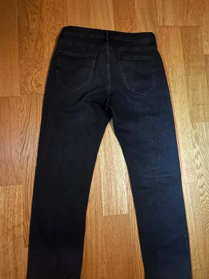 Lee jeans W31 L32 - Säljer ett par gråsvart jeans från Lee med klassisk rak passform. Jeansen har fem fickor, bälteshällor och synliga sömmar. Perfekta för en avslappnad och stilren look.