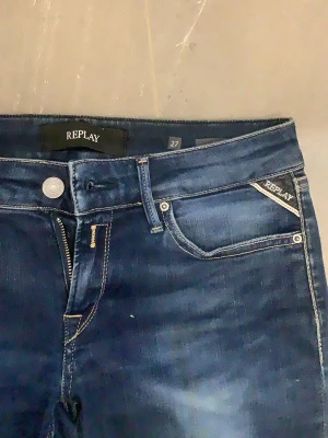 Mörkblå skinny jeans från Replay - Snygga mörkblå skinny jeans från Replay med kontrastsömmar. Klassisk femficksmodell med dragkedja och knapp framtill. Jeansen har en tvättad look och Replay-logga på fickan. Perfekta till vardagslooken!