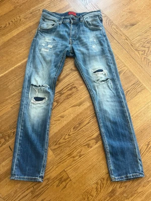 Blå slitna jeans från Jack & Jones - Säljer ett par blå jeans från Jack & Jones med slitningar. Jeansen har fem fickor, normal midja. Materialet är klassisk denim i bomull och de har en avslappnad, trendig look. De är en slim modell så väldigt snygga trendiga jeans, med storleken 30/30