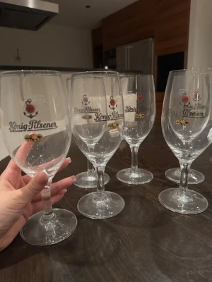  ölglas 6-pack - Säljer ett set med sex eleganta ölglas från König Pilsener. Glasen är genomskinliga med tryckt logga och gulddetaljer. Perfekta för att servera öl med stil hemma eller på fest. Klassisk form med fot och kupa som ger en lyxig känsla.