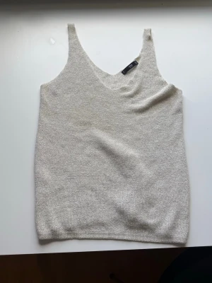 Beige stickad linnetopp från MNG - Säljer en beige stickad linnetopp från MNG Basics. Toppen har smala axelband och v-ringning, perfekt för en enkel och clean look. Materialet är mjukt och lätt, vilket gör den skön att bära under varma dagar.