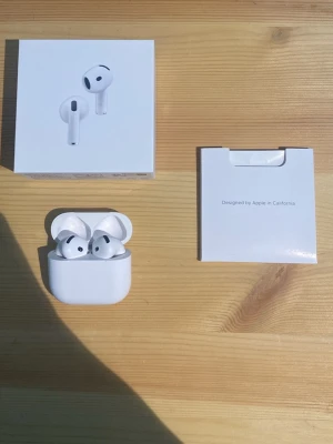 AirPods 4 (ANC) - Säljer ett par vita trådlösa in-ear hörlurar med laddningsetui. Hörlurarna har stilren design med rundade former och sitter bekvämt i öronen. Perfekta för musik, poddar och samtal. Laddningsetui och originalförpackning medföljer.