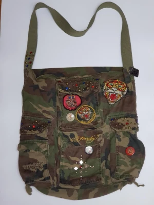 Vintage Ed Hardy Christian Audigier Tote Bag - Vintage Ed Hardy Christian Audigier Camo Canvas Tote Bag with rhinestone patches and badges, 40x40 cm. Jag går INTE ner i pris på annonsen.