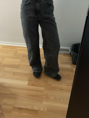 Vida svarta jeans med hög midja - Säljer ett par svarta jeans med hög midja och raka, vida ben. Jeansen har klassisk femficksdesign och är tillverkade i ett kraftigare denimtyg. Perfekta för dig som gillar en avslappnad och trendig stil.