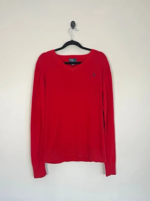 Polo Ralph Lauren Röd V-ringad Tröja Pima Cotton Marinblå Logo Stl L (16/18) - • Storlek: L • Färg: Röd • Passform: Regular Fit  • Krage: V-ringad • Material: 100% bomull  Skick: Plagget är i väldigt fint skick. Eventuella anmärkningar anges alltid tydligt i beskrivningen och visas på bilderna.  Nypris: Cirka 2 000 kr.  📦 Skickas snabbt och packas omsorgsfullt. 💬 Hör gärna av dig om du har frågor eller vill se fler bilder. 🤝 Samfrakt erbjuds vid köp av flera plagg – kika gärna in mina andra annonser!
