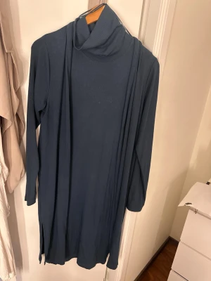 Mörkblå  klänning med polokrage+ cardigan  - Mysig mörkblå klänning kort ärm och hög polokrage. Klänningen är ribbad och har en rak passform med slitsar i sidorna strl M. Cardigan storlek L Perfekt för dig som gillar enkel och stilren design.
