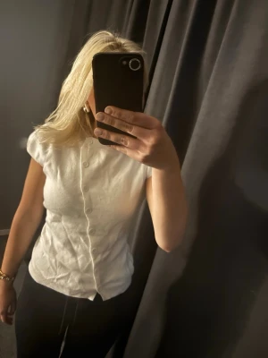 Vit kortärmad kofta från Muséra - Snygg vit kofta från Muséra med korta ärmar och knäppning framtill. Tillverkad i mjukt material som sitter skönt på kroppen. Perfekt att styla med både jeans och kjol för en clean look.