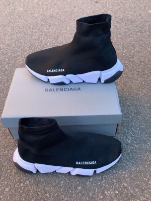 Balenciaga Speed Trainer svarta sneakers - Svarta Balenciaga Speed Trainer sneakers med vit chunky sula och stickad ovandel i textil. Strumpmodell med hög ankel och tydlig Balenciaga-logga på sidan. Snygg och futuristisk design som sticker ut i mängden.