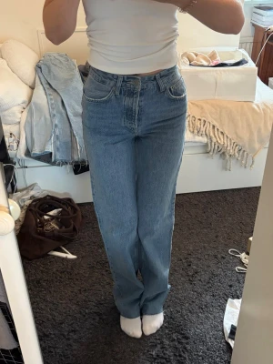 Blå raka jeans med hög midja - Säljer ett par klassiska blå jeans med rak passform och hög midja. Jeansen har fem fickor och stängs med dragkedja och knapp. Perfekta till en enkel topp eller hoodie för en chill look. Aldrig använda, endast testade