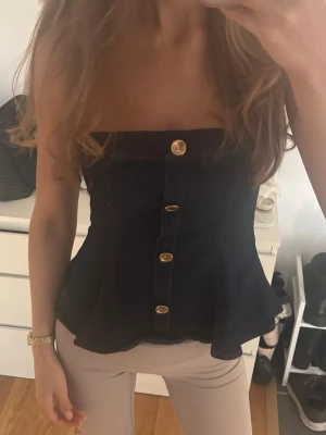axelbandslös jeanstopp - Snygg axelbandslös jeanstopp med guldfärgade knappar framtill. Säljer den då den är lite stor i upptill för mig! Den är xs men skulle säga att den är mer lik en storlek s eller större xs 🌟🌟
