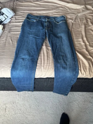 Armani jeans W30 L32 - Säljer ett par klassiska blå jeans med rak passform och fem fickor. Jeansen har gul kontrastsöm och stängs med dragkedja och knapp. Perfekta till vardagslooken och tillverkade i slitstarkt denimtyg.