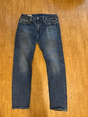 Levi's Premium blå raka jeans - Klassiska blå jeans från Levi's Premium med rak passform och fem fickor. Jeansen har en snygg tvättad look och är tillverkade i slitstarkt denimtyg. Perfekta för en avslappnad och tidlös stil. Billigare vid snabba köp 