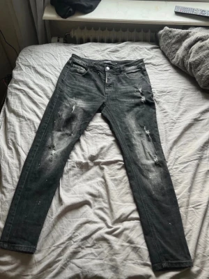 Alessandro Zavetti - Säljer ett par svarta jeans med skinny fit och slitningar på både fram- och baksidan. Jeansen har klassisk femficksdesign och är tillverkade i denim med stretch. Perfekt för dig som gillar en edgy och trendig look.