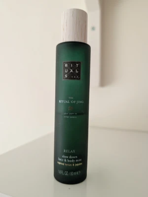 Rituals The Ritual of Jing mist - Rituals The Ritual of Jing Relax hair & body mist med doft av helig lotus och jujube. Flaskan är grön med en vit träliknande kork och rymmer 50 ml. Perfekt för dig som vill ha en lugnande och fräsch doft till både kropp och hår.